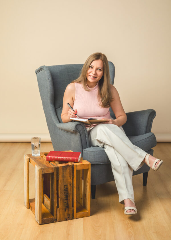 Galya, an online coach in the UAE, seated in an armchair with a notebook